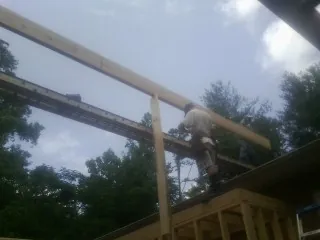 Carpenter setting a ridge beam over a new addition frame — Ice Dam Removal by Roofing Brothers in Cokeville