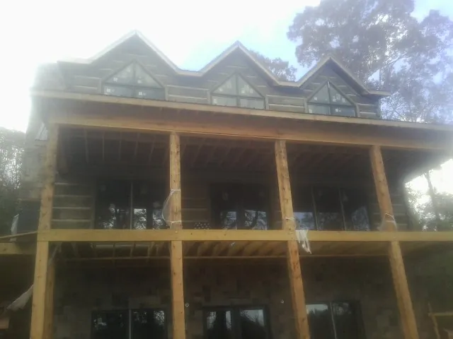 Dormers and porch framing on a large log home under construction — Roof Coating work by our crew in Cokeville