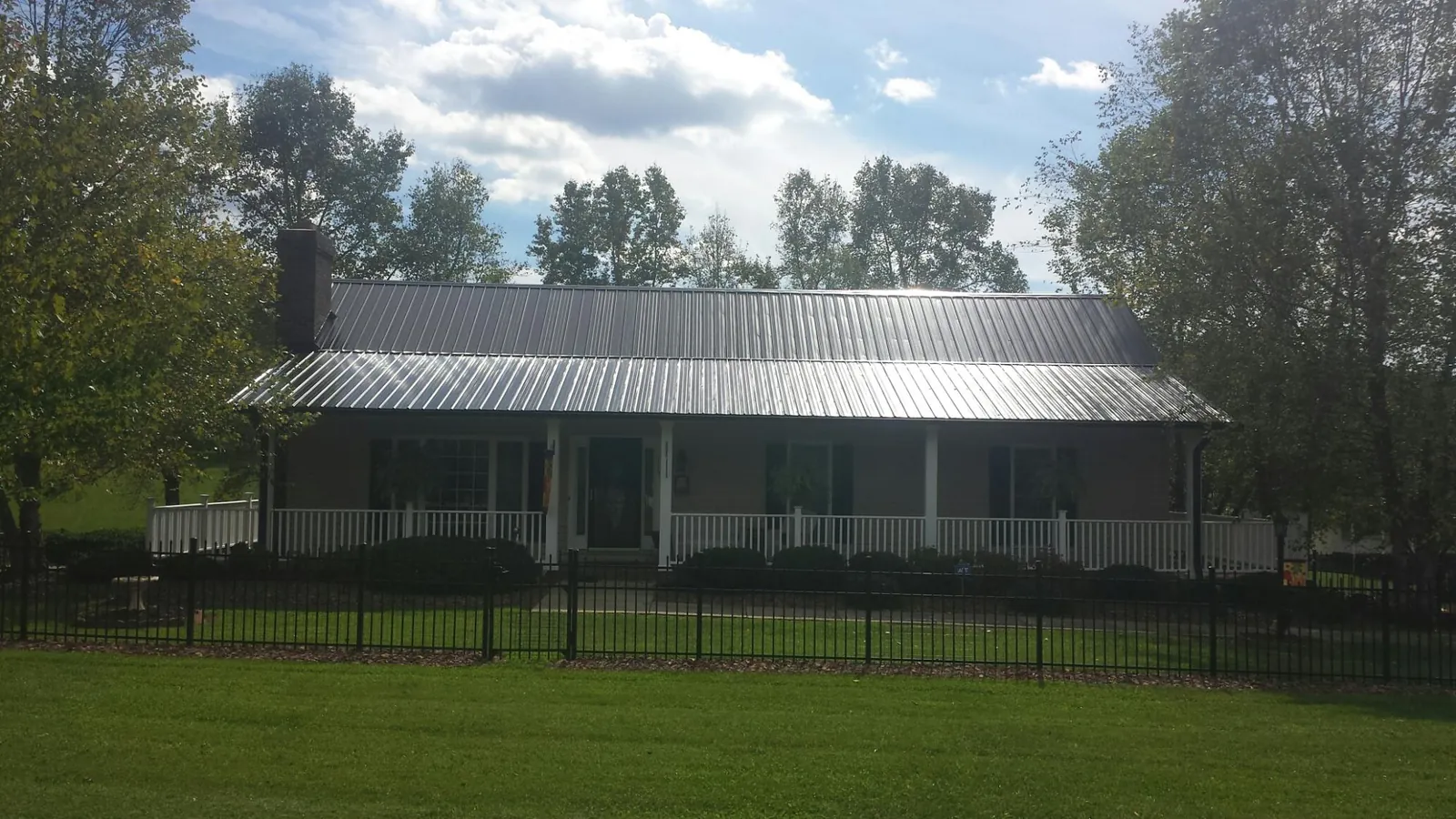 Gray metal roof on a brick ranch with a full width front porch — Gutter Guard Installation work by our crew in Cokeville