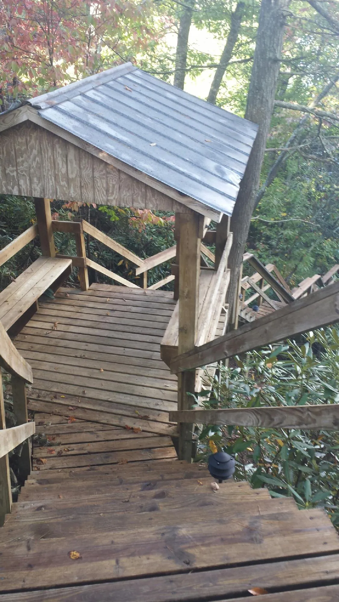 Metal roofed shelter over wooden steps on a wooded walkway — Skylight Repair & Installation work by our crew in Cokeville