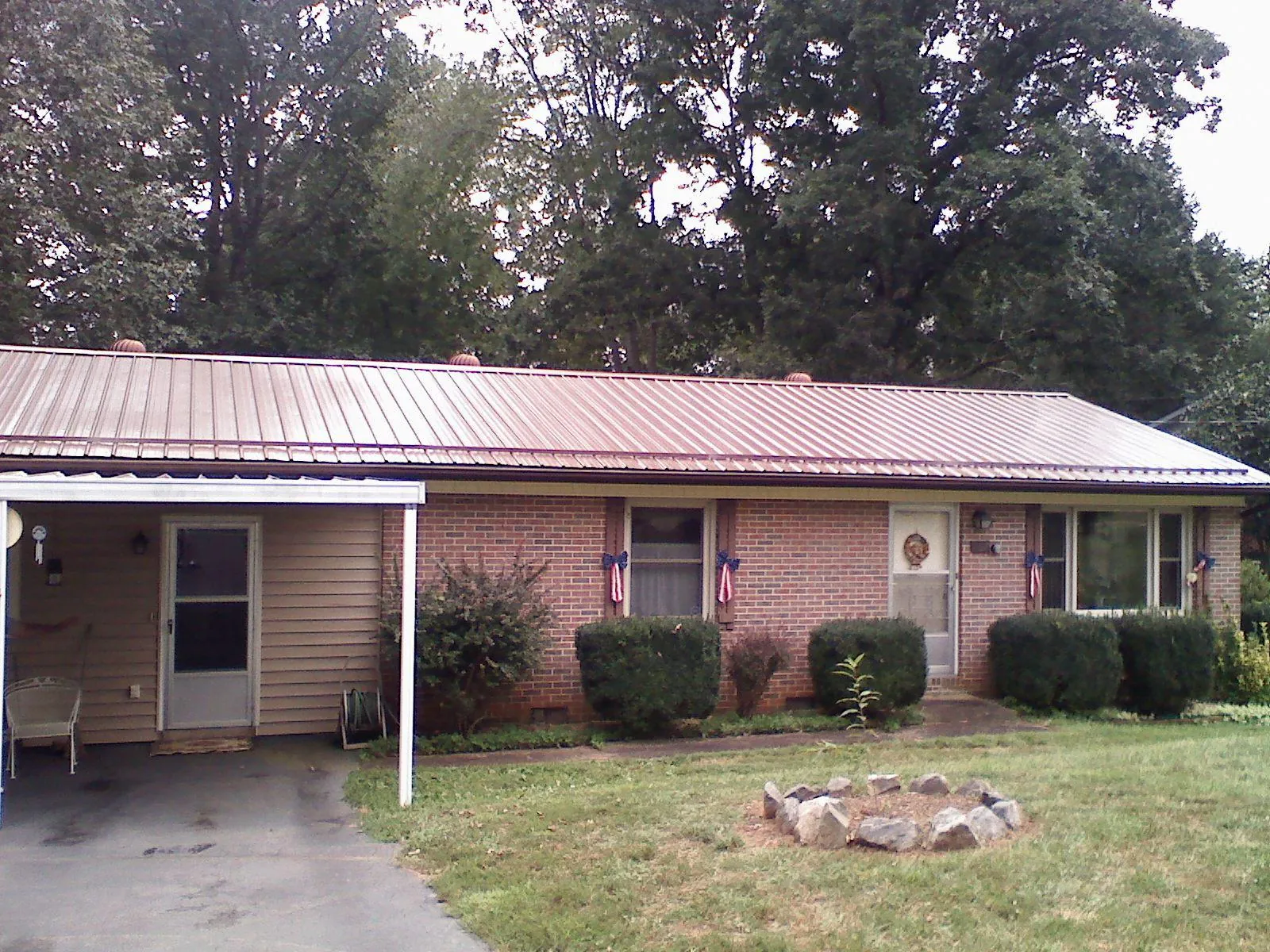 Bronze metal roof and carport on a brick ranch home — Roof Repair work by our crew in Cokeville