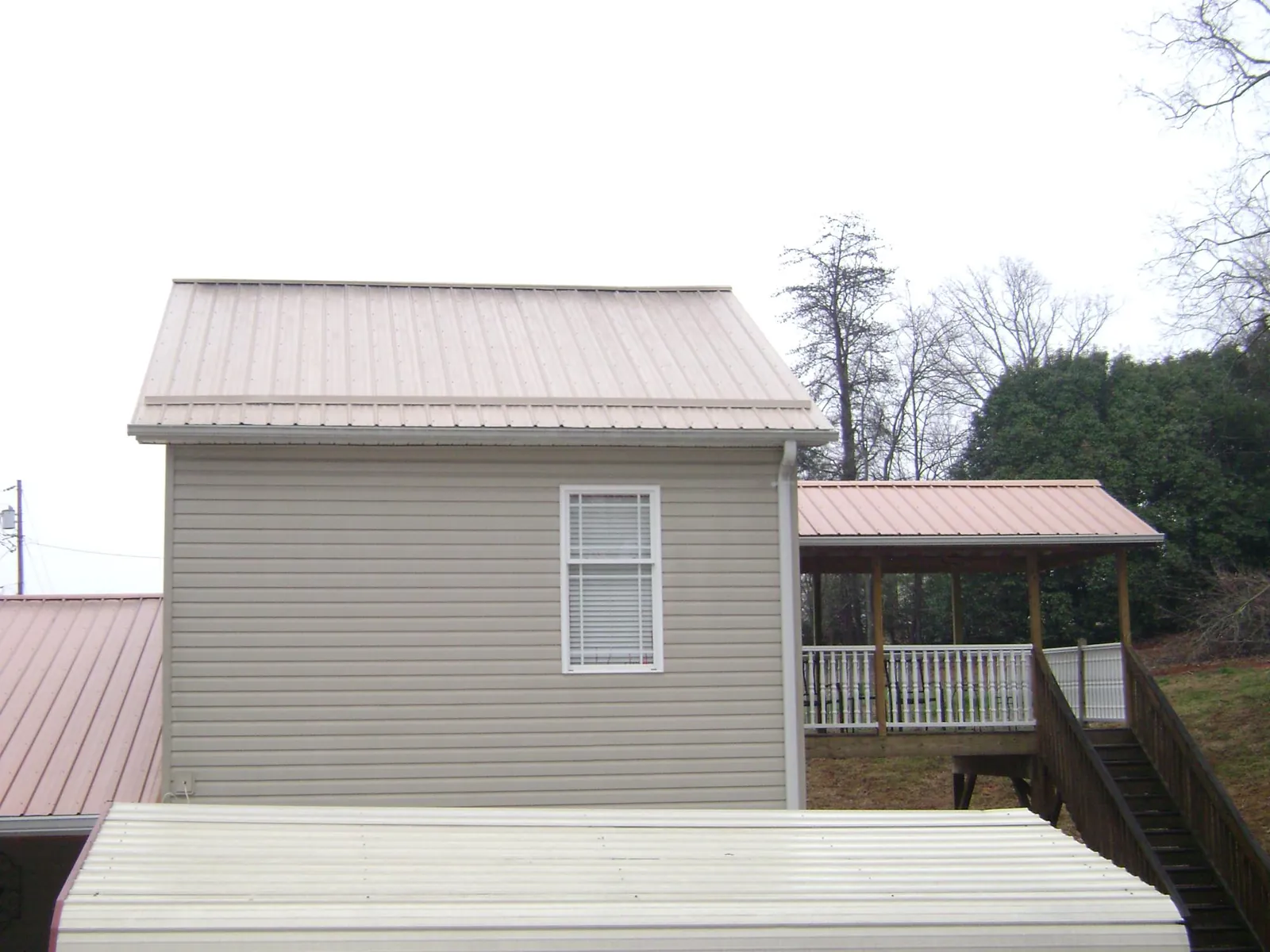 Tan metal roofs on a two story addition and attached porch, from a Roof Replacement job in Cokeville