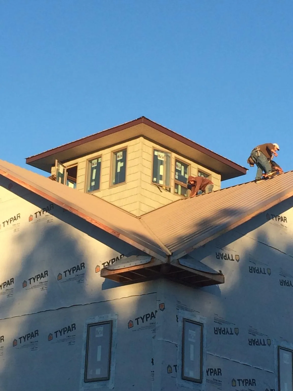 Roofers working around a rooftop cupola on a new metal roof at sunset — Roof Waterproofing in Cokeville by Roofing Brothers